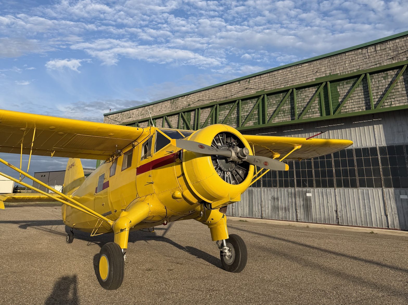 Yellow Noorduyn Norseman aircraft parked outside the historic hangar at the Commonwealth Air Training Plan Museum in Brandon, Manitoba.